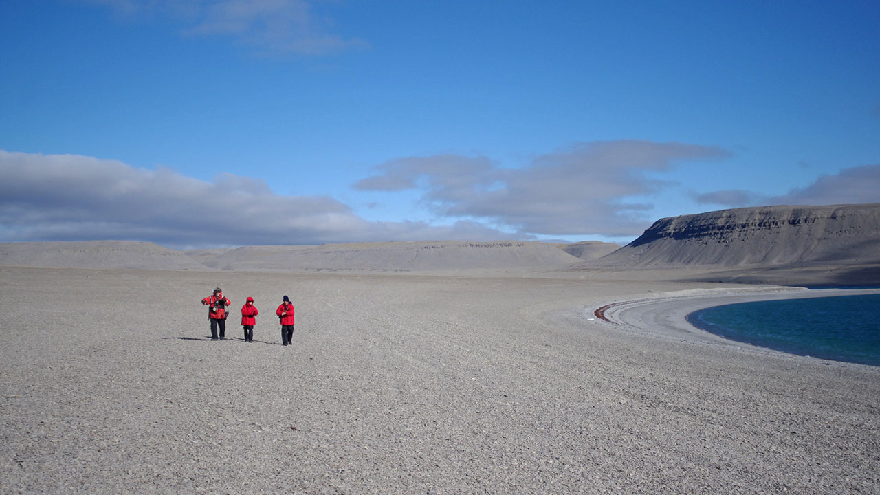 Expedition staff walk across the vegetation free expanses of Beechey Island.