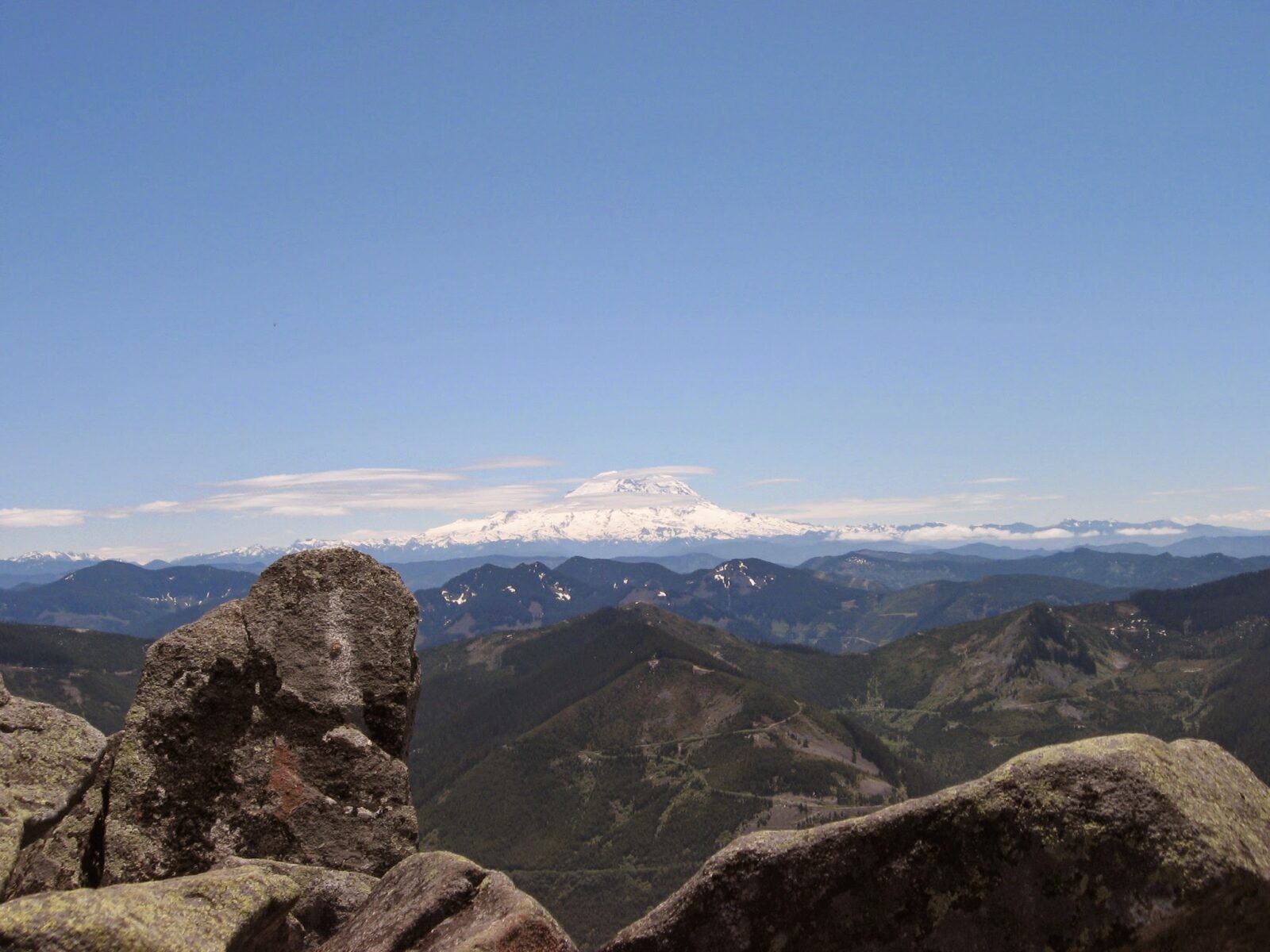 Rocks in the foreground and a large mountain in the background against a blue sky