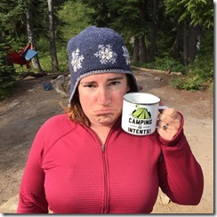 Woman frowning wearing a hat and holding a mug