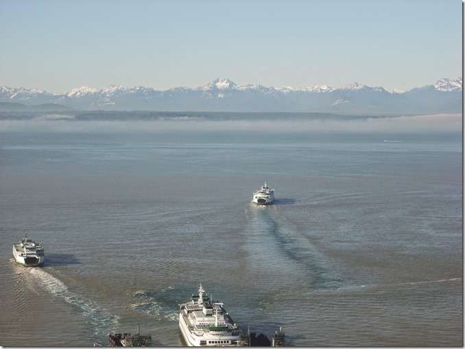 Three ferries near the dock, in the distance are snow capped mountains