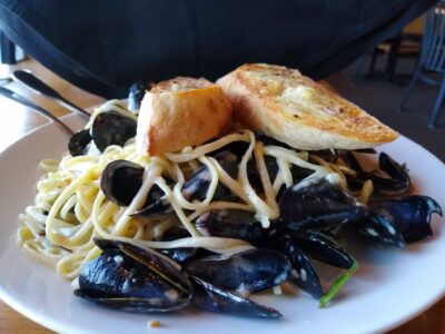 A plate of pasta with mussels and bread