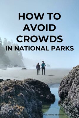 Foggy and sunny beach with rocks and two people. How to avoid crowds in national parks is printed on the photo