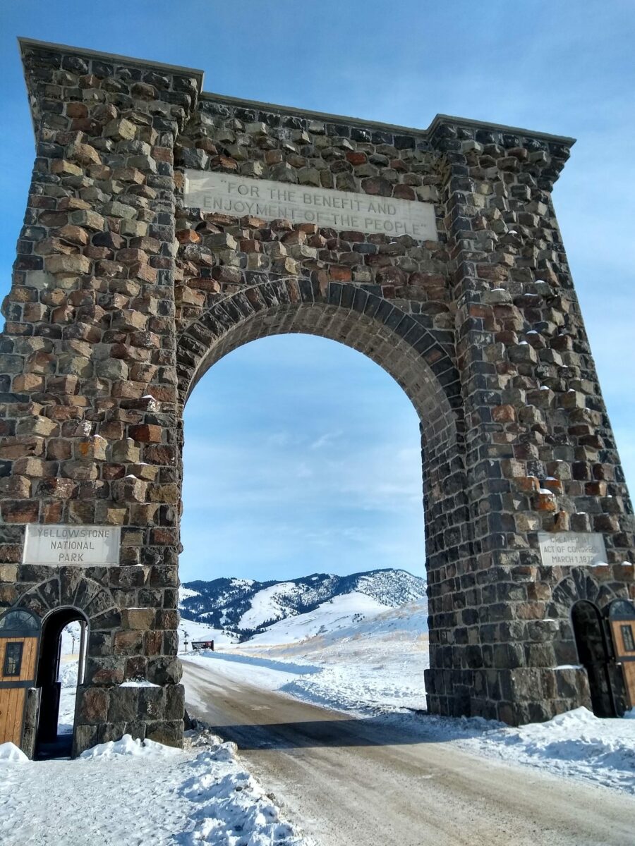 Large stone arch over the road says Yellowstone National Park and "For the Benefit and Enjoyment of the People"