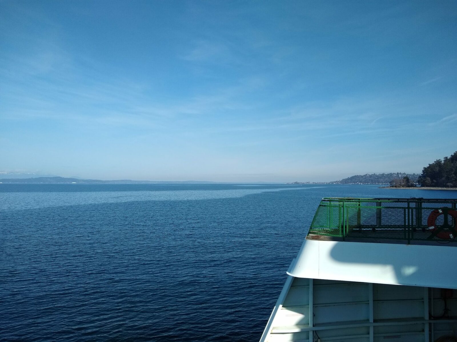 part of a ferry boat and the shoreline on a sunny day