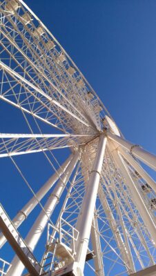 A large painted white metal ferris wheel against a blue sky