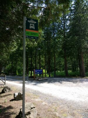 A parking lot at a trailhead in the forest with a bus stop.