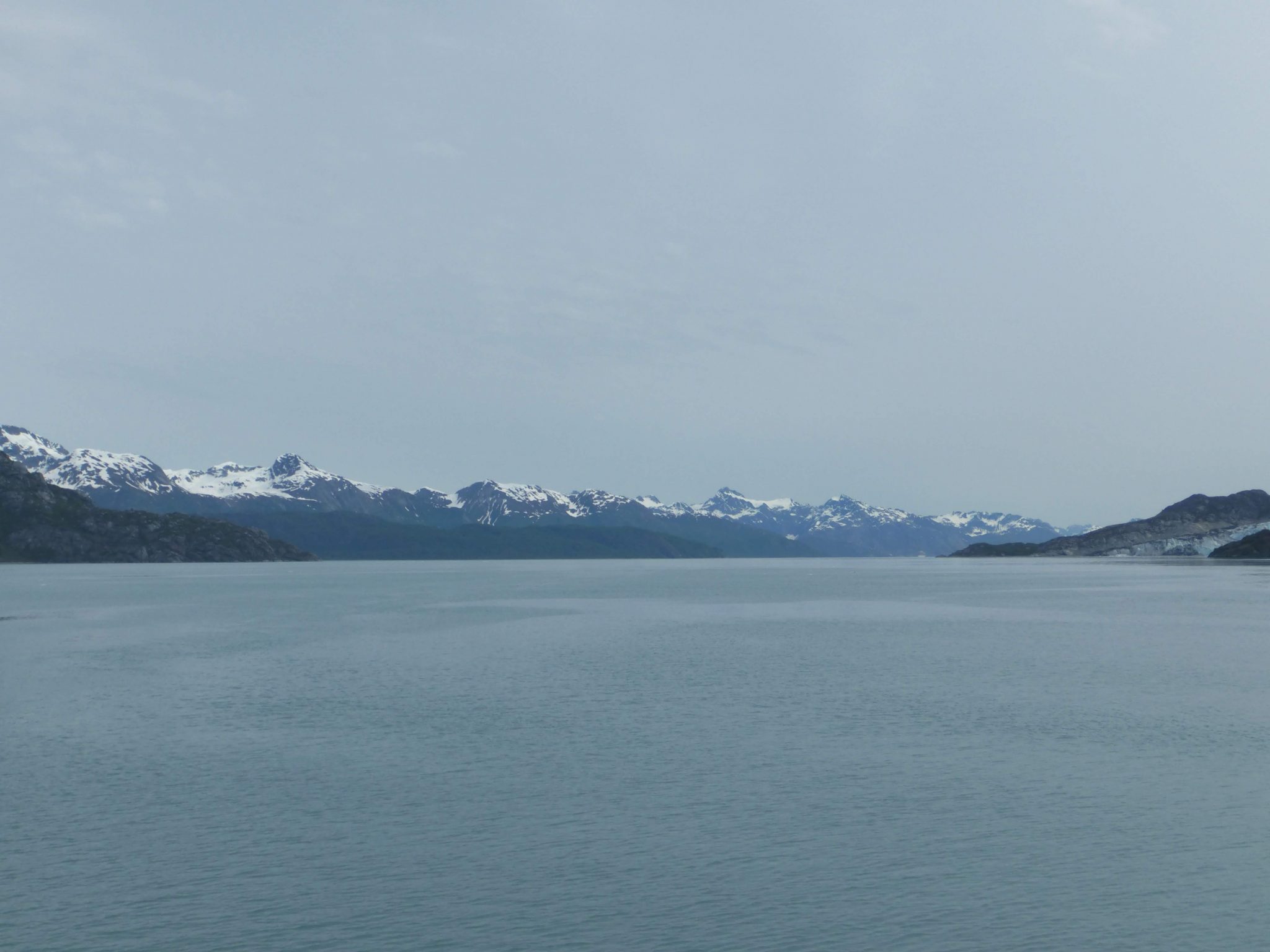 Distant snow capped mountains frame the water of Glacier Bay