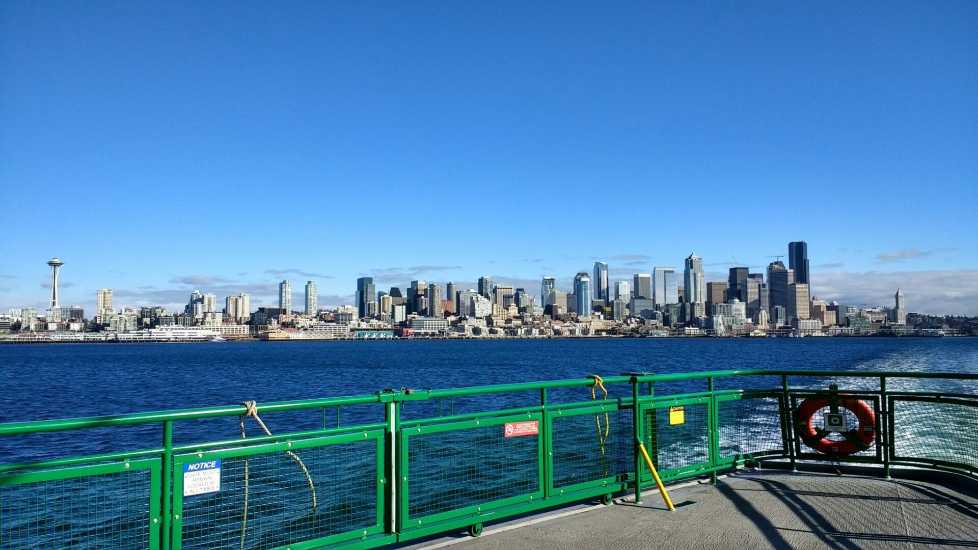 The Seattle city skyline from the ferry. The deck of the ferry is in the foreground. Heading to Bainbridge on the ferry is an important part of a Seattle Itinerary