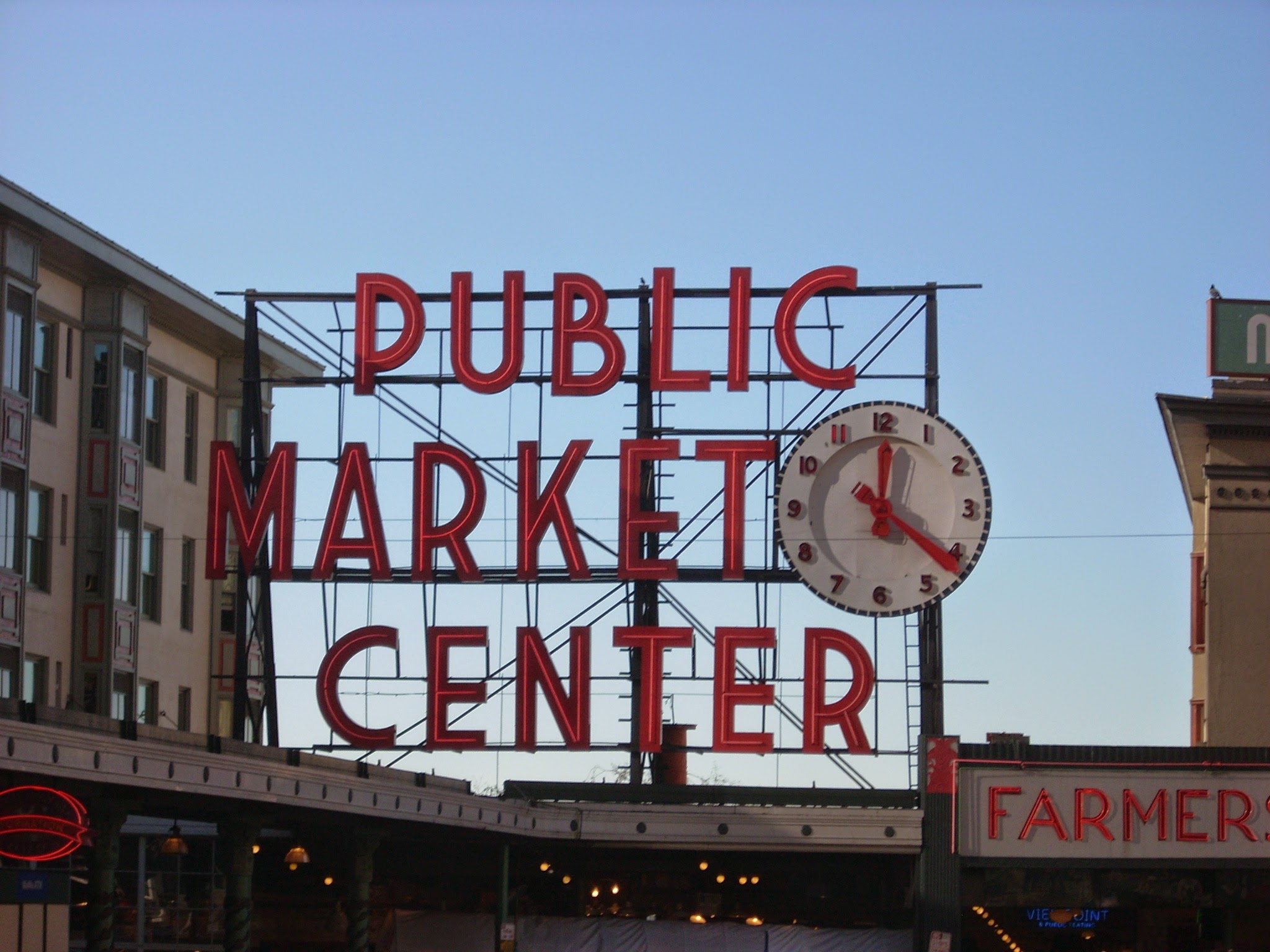 The Public Market Center sign in Seattle. The sign has large red letters and a red and white clock.