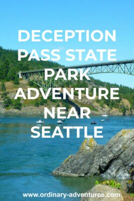 A high green metal bridge spans a narrow channel above blue water with several fishing boats and a sailboat passing under. Around the bridge and water are rocky headlands and forested hillsides. It's a blue sky sunny day. Text reads: Deception Pass State Park adventure near Seattle