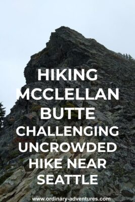 The summit block on the McClellan Butte hike. It is an angled gray rock sticking into the fog, surrounded with a few evergreen trees. Text reads: hiking McClellan Butte challenging uncrowded hike near seattle