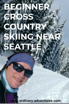 A woman wearing sunglasses smiles on a cross country ski trail. There are snow covered evergreen trees all around her. Text reads: Beginner cross country skiing near Seattle