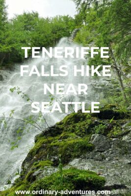 Looking up from the base of a steep waterfall with water and spray coming down a steep rock face. There are rocks and trees surrounding it. Text reads: Teneriffe Falls hike near Seattle