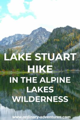 An alpine lake reflects the mountains around it. Text reads: Lake Stuart hike in the Alpine Lakes wilderness