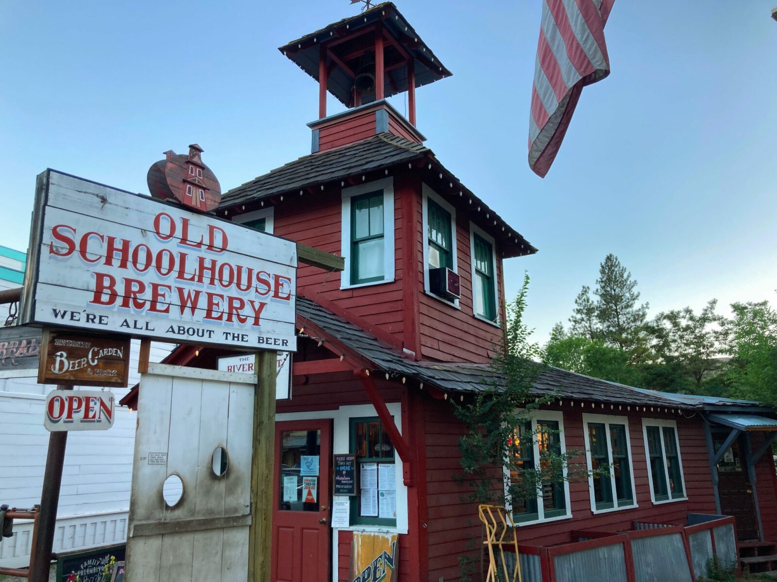 A historic tiny red schoolhouse with a sign in front that says Old Schoolhouse Brewery in Winthrop, Washington, near North Cascades National Park