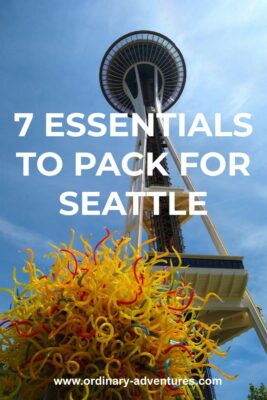 Looking up at the Space Needle from below against a blue sky. There is a yellow glass sculpture in the foreground. Text reads: 7 essentials to pack for Seattle