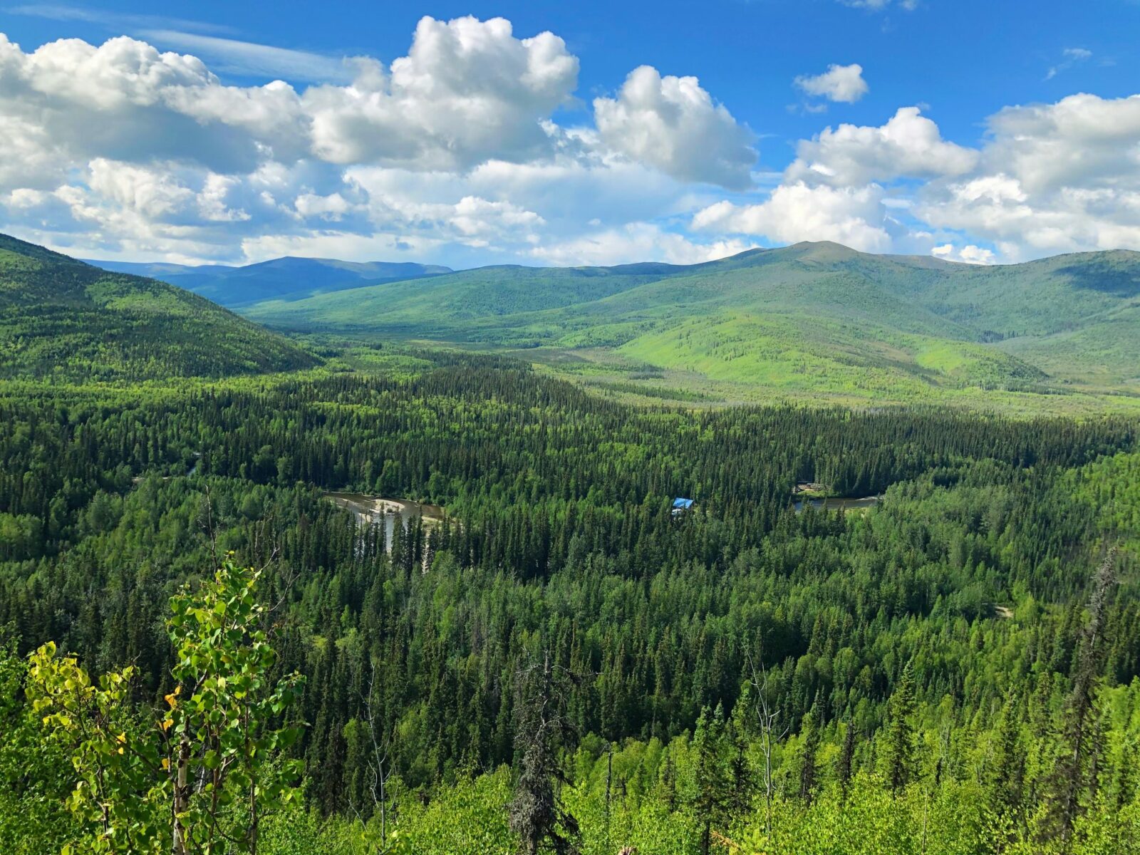 View of forested hillsides and a river below on a partly cloudy day from the angel rocks trail