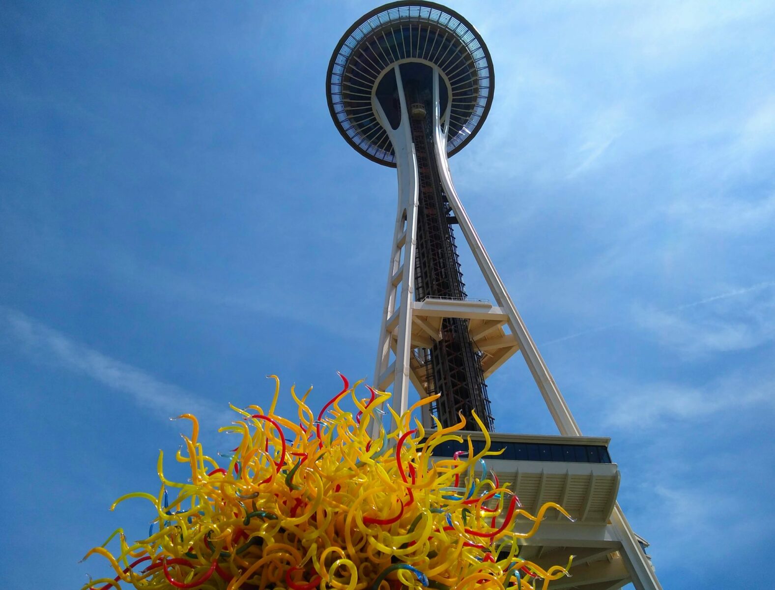 The Space Needle against the blue sky with a yellow glass sculpture in the foreground, an important part of any seattle itinerary