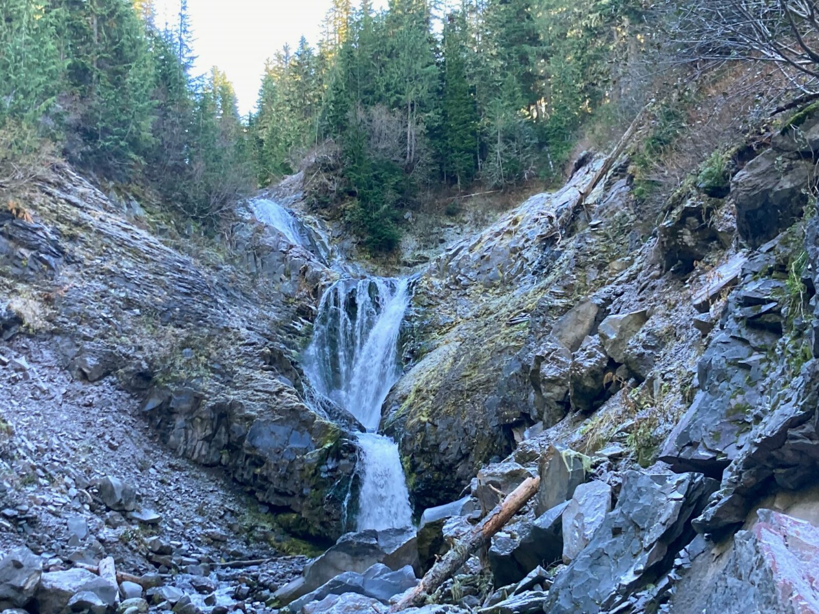 A waterfall tumbling between rocks in a ravine in the forest on the Comet Falls trail in Mt Rainier National park