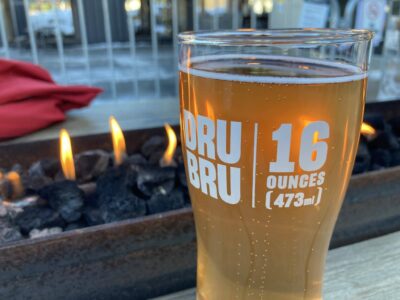 A beer on a picnic table in front of a propane fire