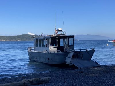 A metal landing boat at a gravel beach ready to load campers and hikers. 