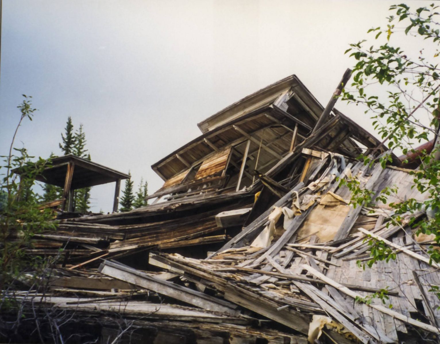 A unique thing to do in dawson city is visit the paddle wheeler graveyard, a collection of crushed old ships damaged by the river. A pile of crumpled wood takes up the photo, an old pilot house partially collapsed can be seen at the top of the pile