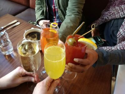 Four pairs of hands each hold a cocktail in the middle of a table. 