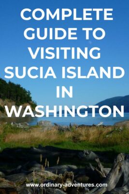 driftwood and grass at the head of a small bay surrounded by forests. Text reads complete guide to visiting sucia island in washington state